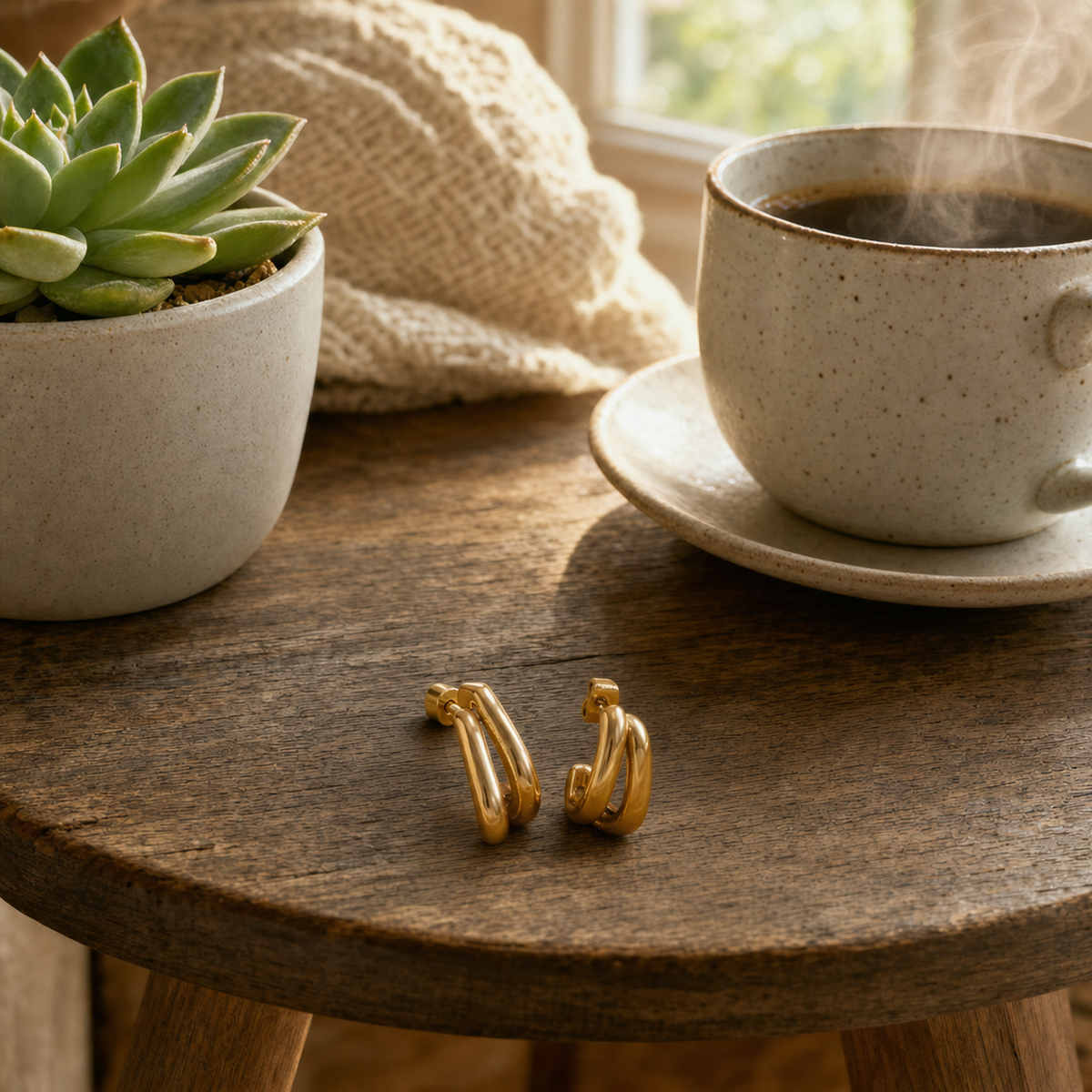 18k gold plated stainless steel double band chunky C-hoop earrings, high-polish mirror finish close-up, hypoallergenic tarnish resistant stacked hoop earrings, Dallas Texas, displayed on a round wood side table with a succulent and coffee