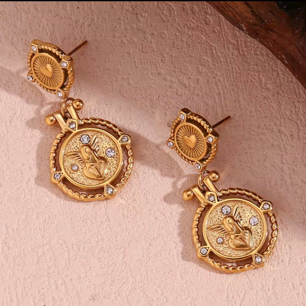 18k antiqued gold Sacred Heart coin drop earrings with CZ crystal square stud top and engraved winged heart medallion displayed on wet pearlescent surface — hypoallergenic water-resistant tarnish-resistant vintage statement earrings by The Intertwined Collective, Dallas Texas