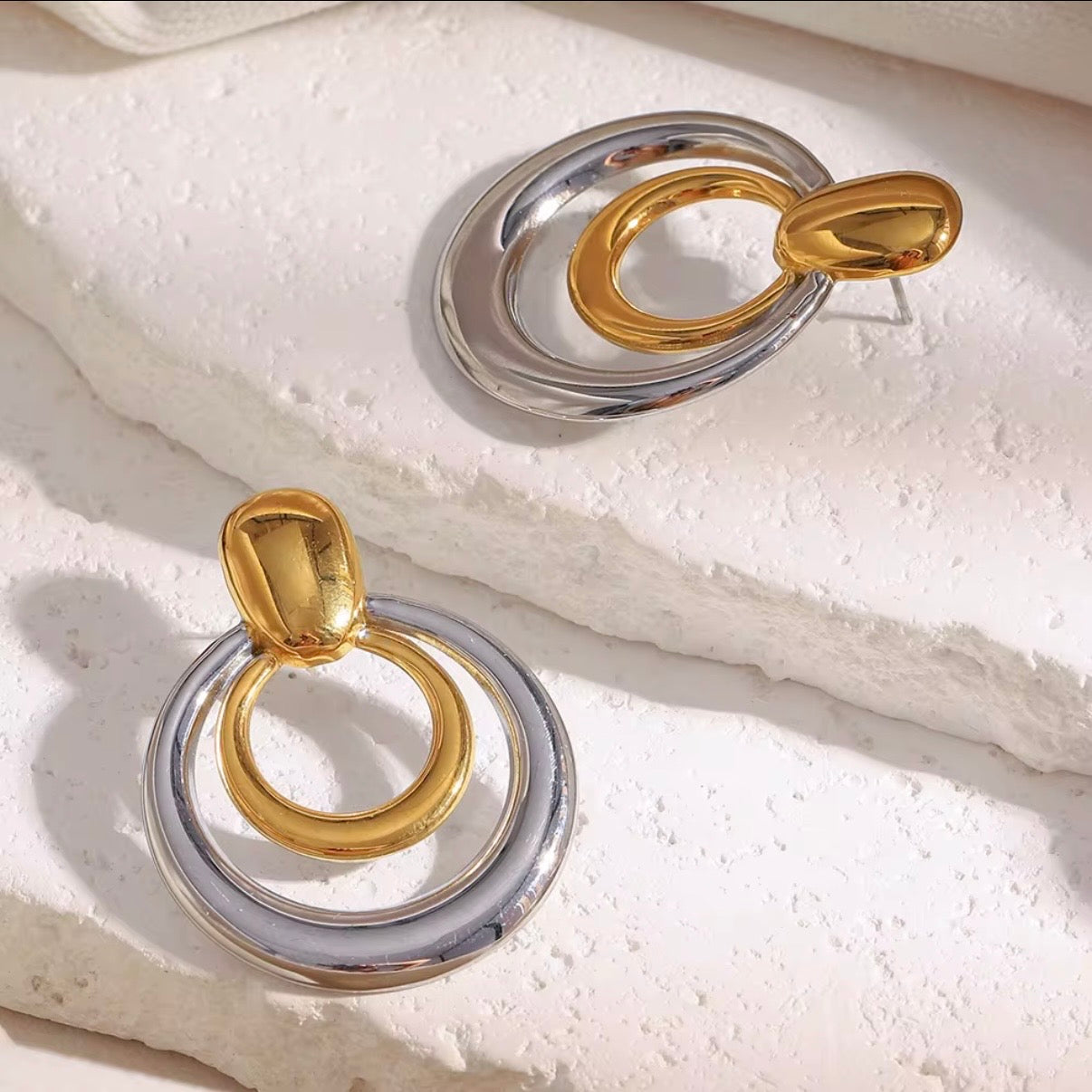 Two-tone gold and silver triple concentric circle drop earrings with dome stud displayed on white satin fabric — hypoallergenic water-resistant tarnish-resistant bold statement earrings by The Intertwined Collective, Dallas Texas
