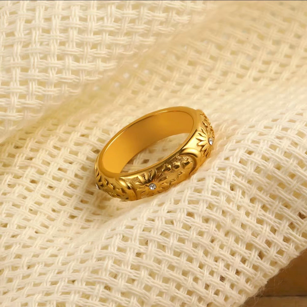 Gold matte celestial band ring with embossed sun, moon and star engravings and tiny CZ crystal accents on cream background – hypoallergenic water and tarnish resistant ring