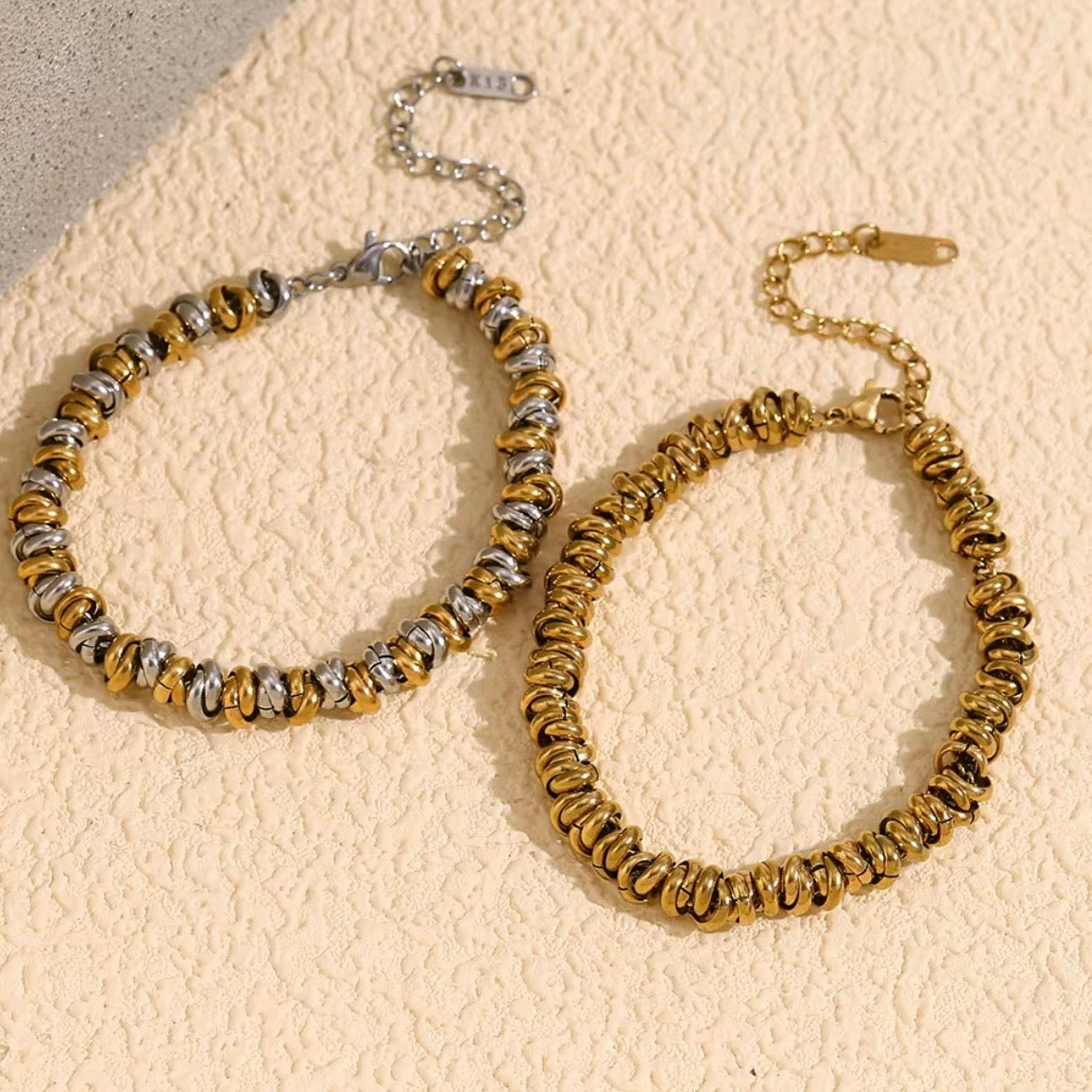 Gold and two‑tone ripple bead bracelets with stacked beads arranged on textured stone surface – hypoallergenic water and tarnish resistant beaded bracelets