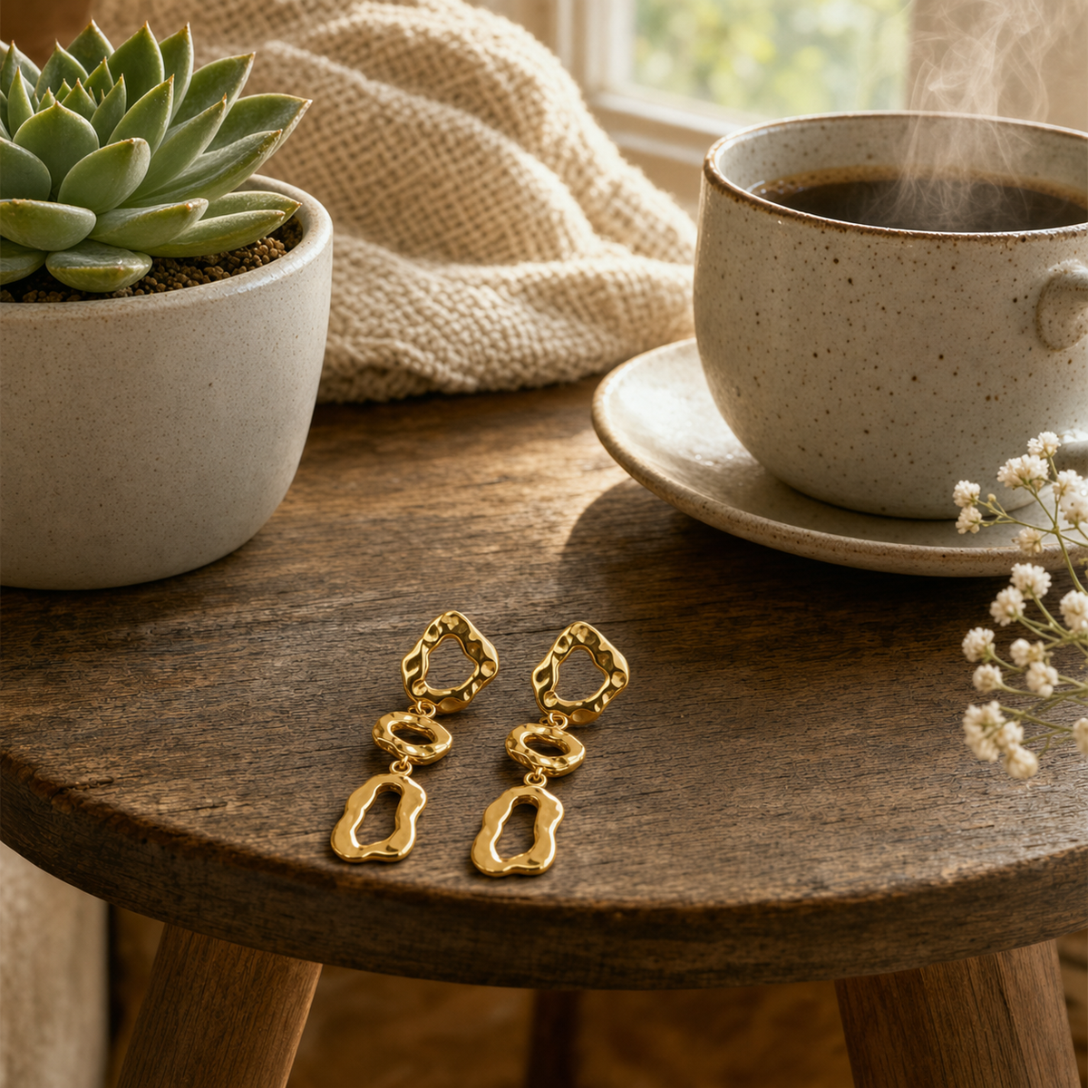 18k gold triple cascading open-frame drop earrings with hammered molten organic finish displayed on a round wood side table with a succulent and coffee— hypoallergenic water-resistant tarnish-resistant statement earrings by The Intertwined Collective, Dallas Texas