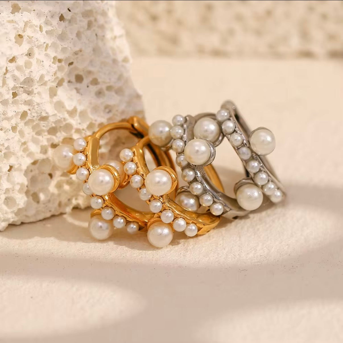 Gold and silver pearl cluster huggie hoop earrings with graduated faux pearl accent displayed on neutral stone surface — hypoallergenic water-resistant tarnish-resistant dainty stackable huggies by The Intertwined Collective, Dallas Texas