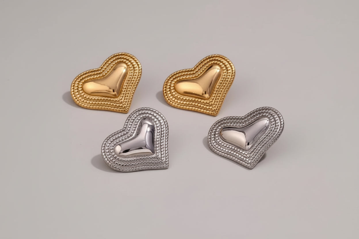 Heart-shaped earrings in gold and silver on a textured surface