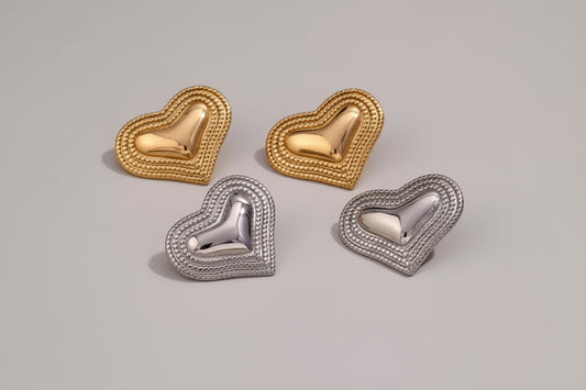 Heart-shaped earrings in gold and silver on a textured surface