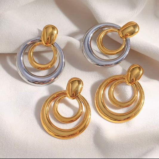 Gold and two-tone gold and silver triple concentric circle drop earrings with dome stud displayed on white satin fabric — hypoallergenic water-resistant tarnish-resistant bold statement earrings by The Intertwined Collective, Dallas Texas
