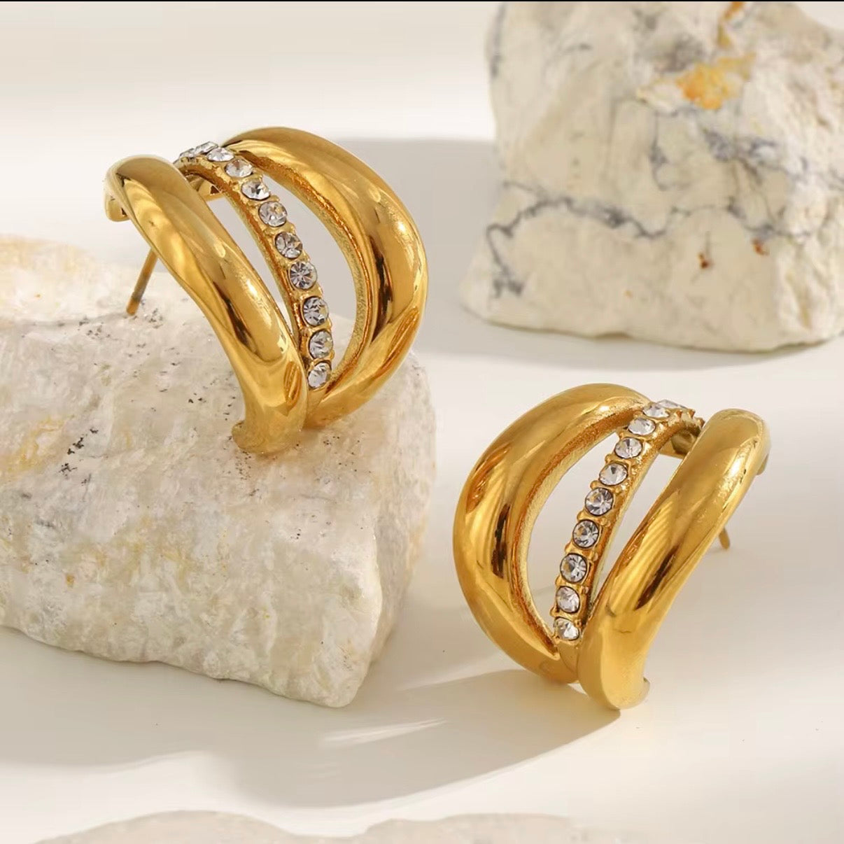 18k gold triple-band hoop earrings with CZ crystal center row displayed on white stone — hypoallergenic water-resistant tarnish-resistant chunky statement hoops by The Intertwined Collective, Dallas Texas