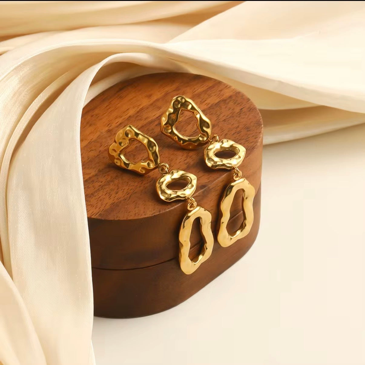 18k gold triple cascading open-frame drop earrings with hammered molten organic finish displayed on wooden tray with cream ribbon — hypoallergenic water-resistant tarnish-resistant statement earrings by The Intertwined Collective, Dallas Texas