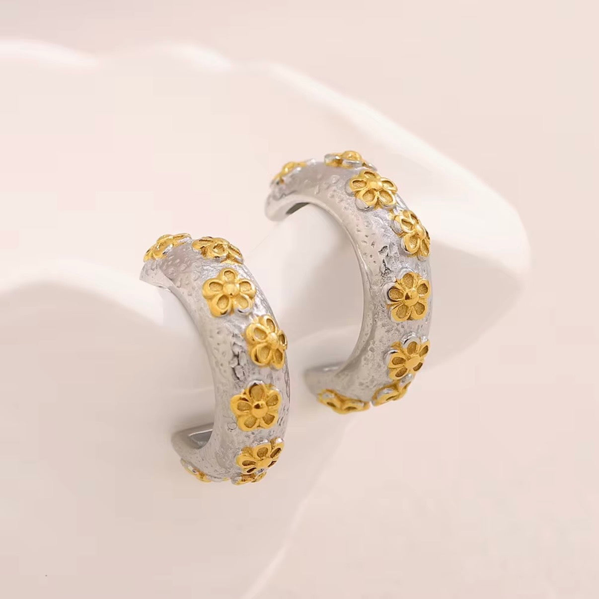 Gold textured huggie hoop earrings with raised floral pattern and tiny crystal accents on black earring card – hypoallergenic, water- and tarnish‑resistant mini hoops