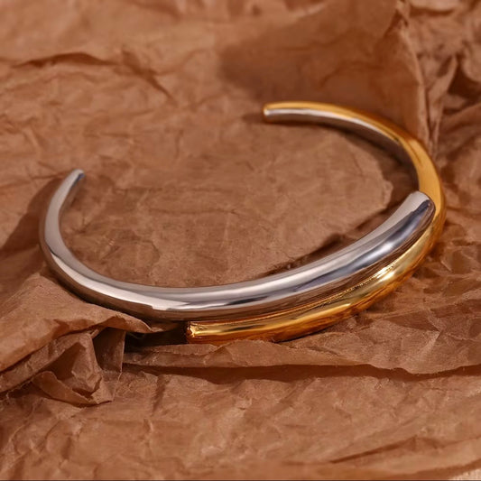 Two‑tone open band ring with overlapping high‑polish silver and gold arcs displayed on crinkled brown paper – hypoallergenic water and tarnish resistant mixed metal ring