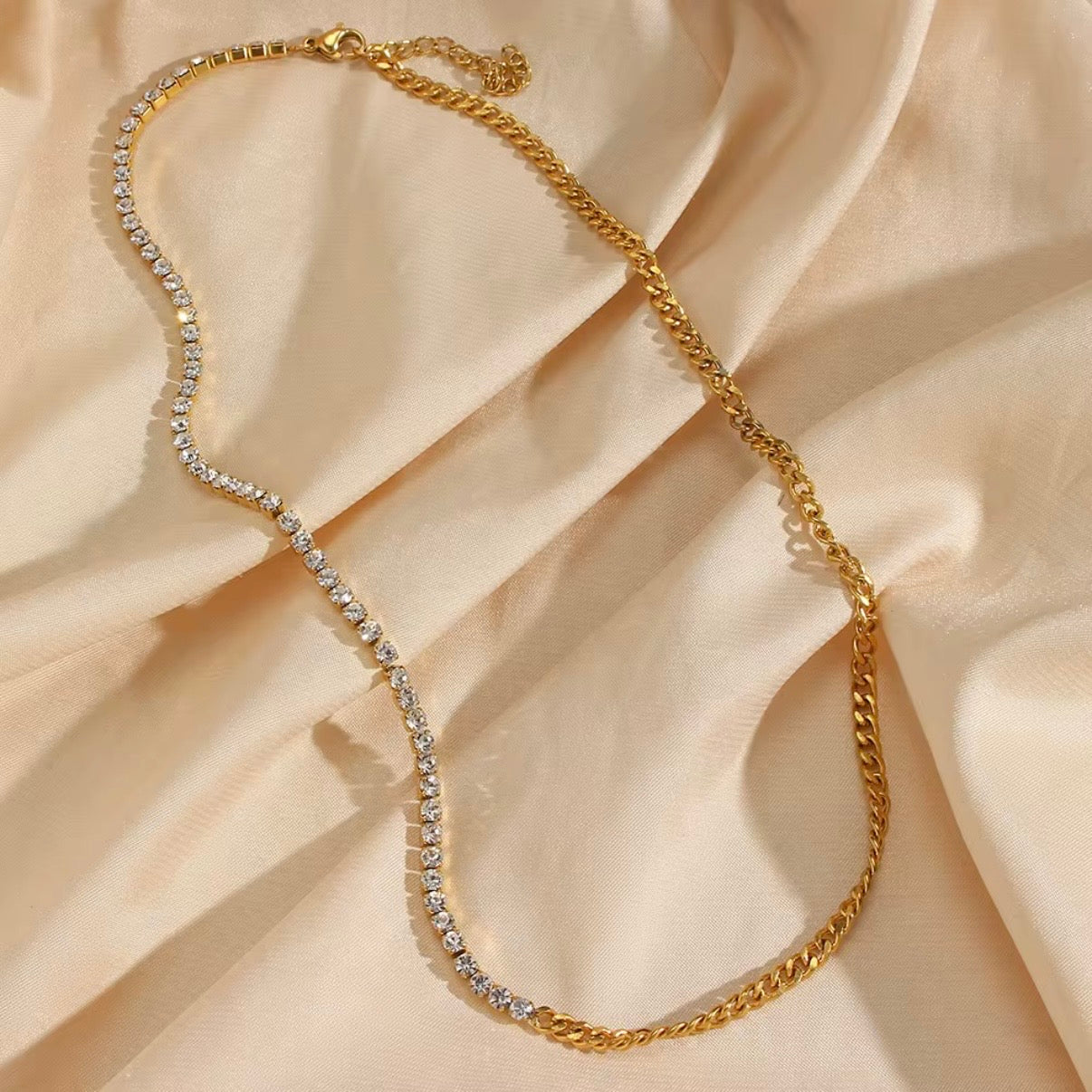 Gold split necklace with half CZ tennis strand and half gold curb chain displayed on soft beige fabric – hypoallergenic water and tarnish resistant necklace