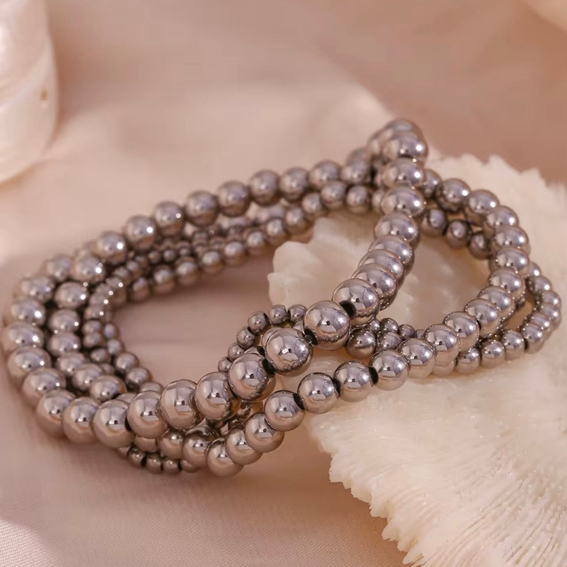 Silver stretch bead bracelets in  3, 4, 5 and 6 mm sizes stacked together on soft fabric – hypoallergenic water and tarnish resistant beaded bracelets