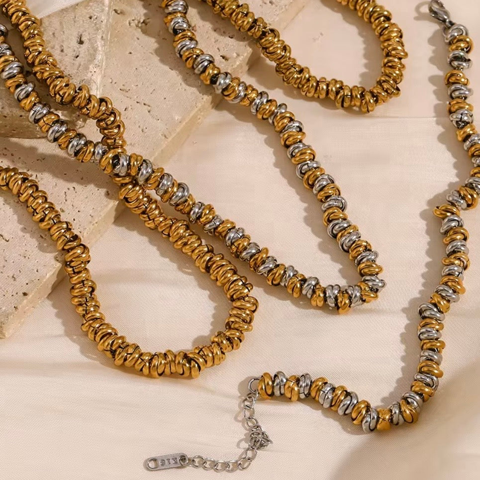 Gold and two‑tone stacked ripple bead necklaces draped over textured stone surface – hypoallergenic water and tarnish resistant beaded chain necklace