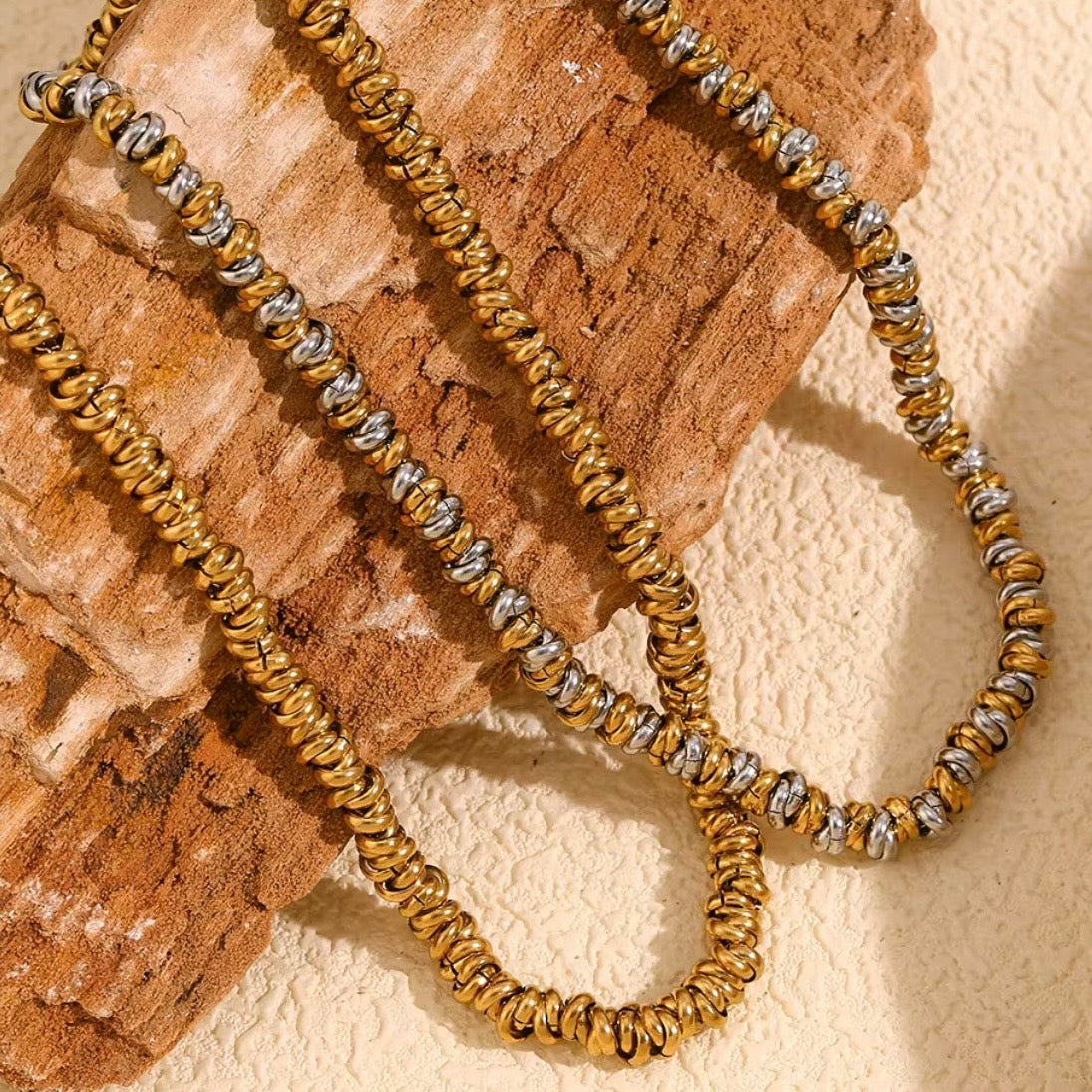 Gold and two‑tone stacked ripple bead necklaces draped over textured stone surface – hypoallergenic water and tarnish resistant beaded chain necklace