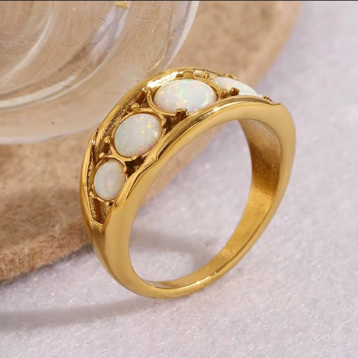 Gold ring with white stones on a textured surface