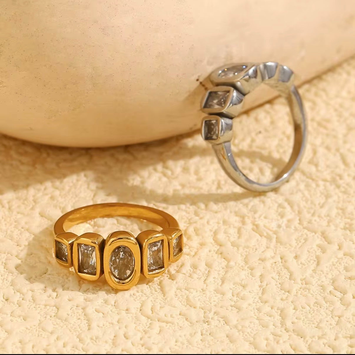 18k gold plated and silver tone stainless steel five-stone mixed-cut CZ bezel band ring with oval, emerald-cut, and princess-cut clear cubic zirconia stones, hypoallergenic tarnish resistant fine jewelry-inspired ring by The Intertwined Collective