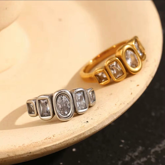 18k gold plated and silver tone stainless steel five-stone mixed-cut CZ bezel band ring with oval, emerald-cut, and princess-cut clear cubic zirconia stones, hypoallergenic tarnish resistant fine jewelry-inspired ring by The Intertwined Collective