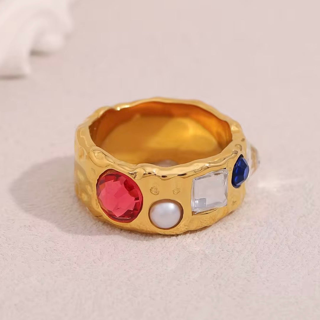 18k gold plated stainless steel wide hammered band ring with mixed scattered stones including red CZ, pearl, clear CZ, and blue CZ, maximalist vintage-inspired statement ring by The Intertwined Collective