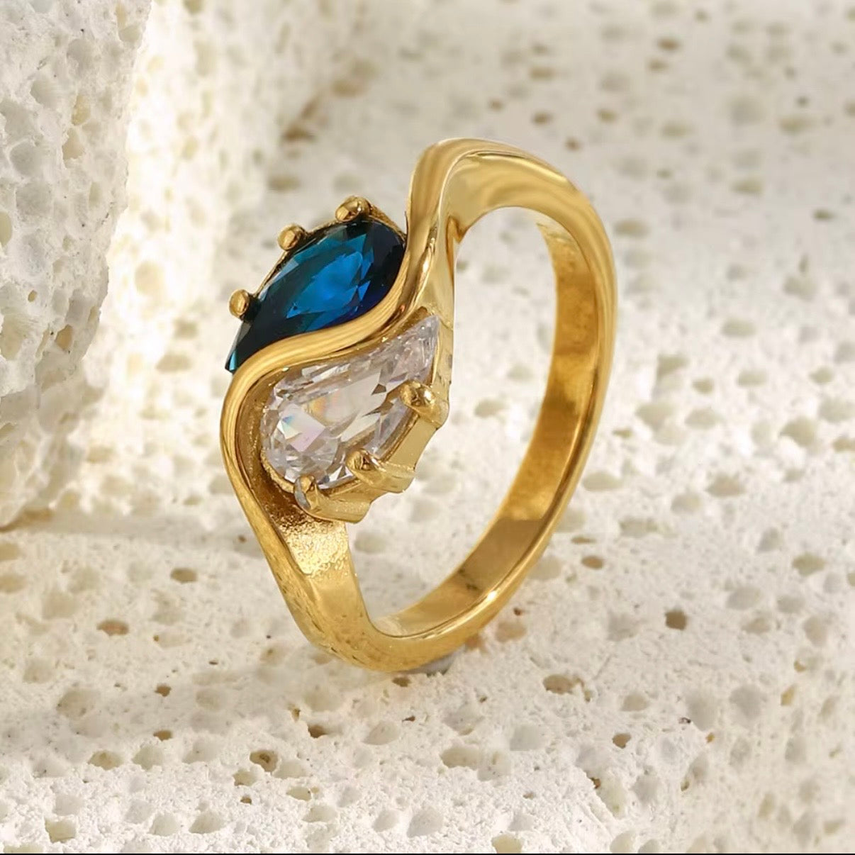 18k gold plated stainless steel toi et moi bypass ring with dual prong-set pear-cut sapphire blue and clear CZ stones in a fluid wave bypass setting, hypoallergenic tarnish resistant bridal-inspired ring by The Intertwined Collective
