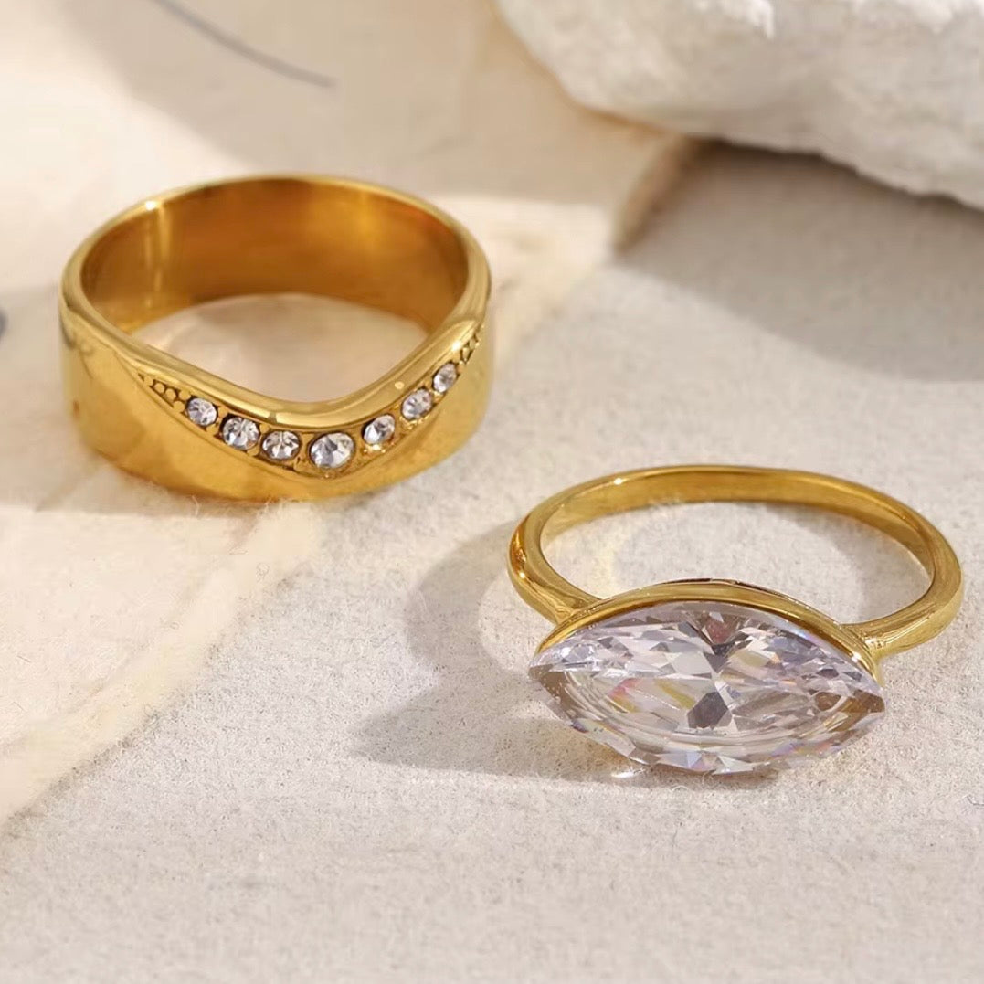 18k gold plated stainless steel two-ring bridal set featuring a wide pavé CZ diagonal band and a marquise-cut CZ bezel solitaire ring, hypoallergenic tarnish resistant fine jewelry-inspired ring set by The Intertwined Collective