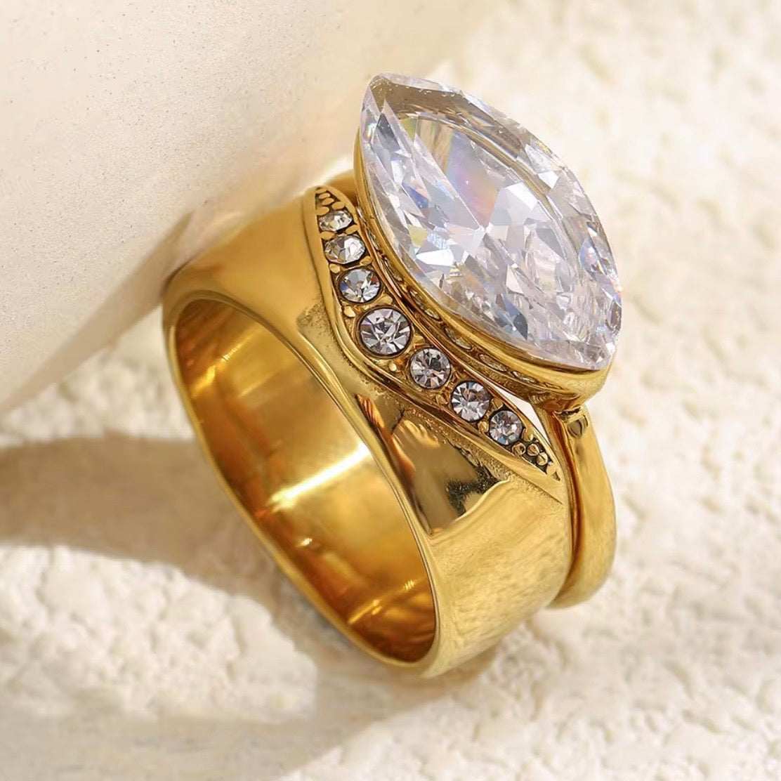 18k gold plated stainless steel two-ring bridal set featuring a wide pavé CZ diagonal band and a marquise-cut CZ bezel solitaire ring, hypoallergenic tarnish resistant fine jewelry-inspired ring set by The Intertwined Collective