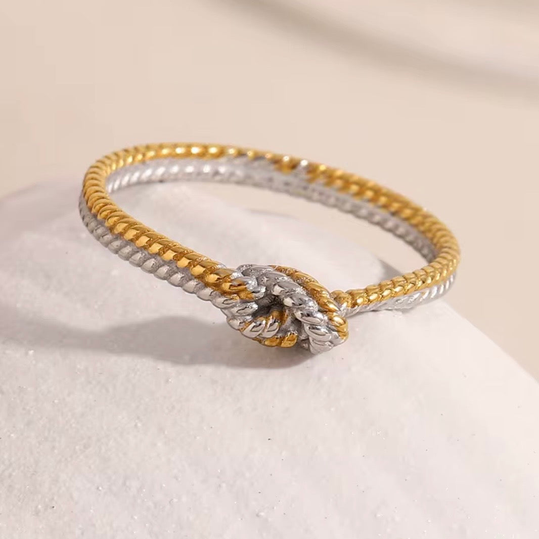 Two-tone stainless steel twisted rope knot ring with intertwined 18k gold plated and silver tone rope strands tied in a central knot, hypoallergenic tarnish resistant symbolic love ring by The Intertwined Collective