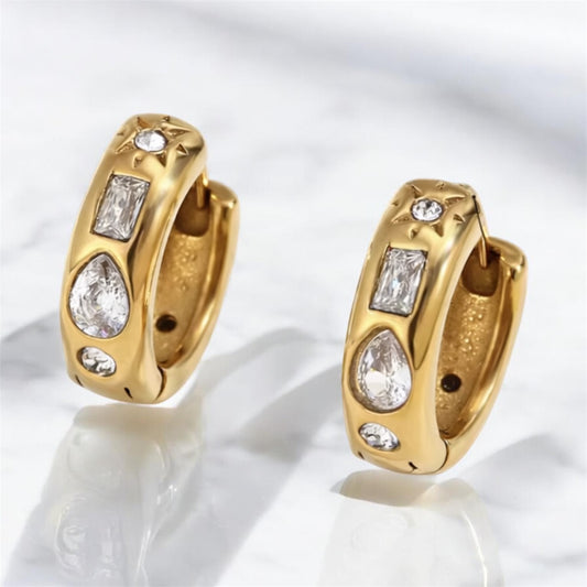 Chunky gold huggie hoop earrings with mixed pear, baguette, and round CZ stones and starburst detailing on marble surface – also available in silver, hypoallergenic water and tarnish resistant