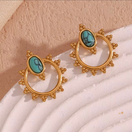 18k gold turquoise oval stone sun halo stud earrings with beaded sunburst frame and open circle drop displayed on white ridged surface — hypoallergenic water-resistant tarnish-resistant boho statement studs by The Intertwined Collective, Dallas Texas
