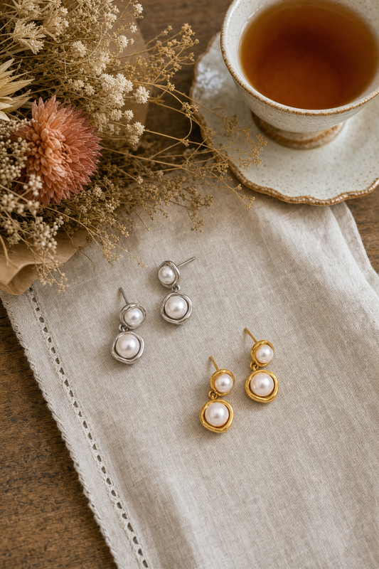18k gold plated and silver tone stainless steel double pearl wrapped drop earrings in gold and silver, hypoallergenic tarnish resistant pearl drop earrings by The Intertwined Collective, Dallas Texas — displayed on a linen napkin with a ceramic teacup of tea and dried florals